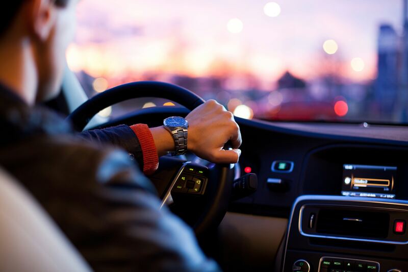 A driver's hands on the steering wheel at dusk